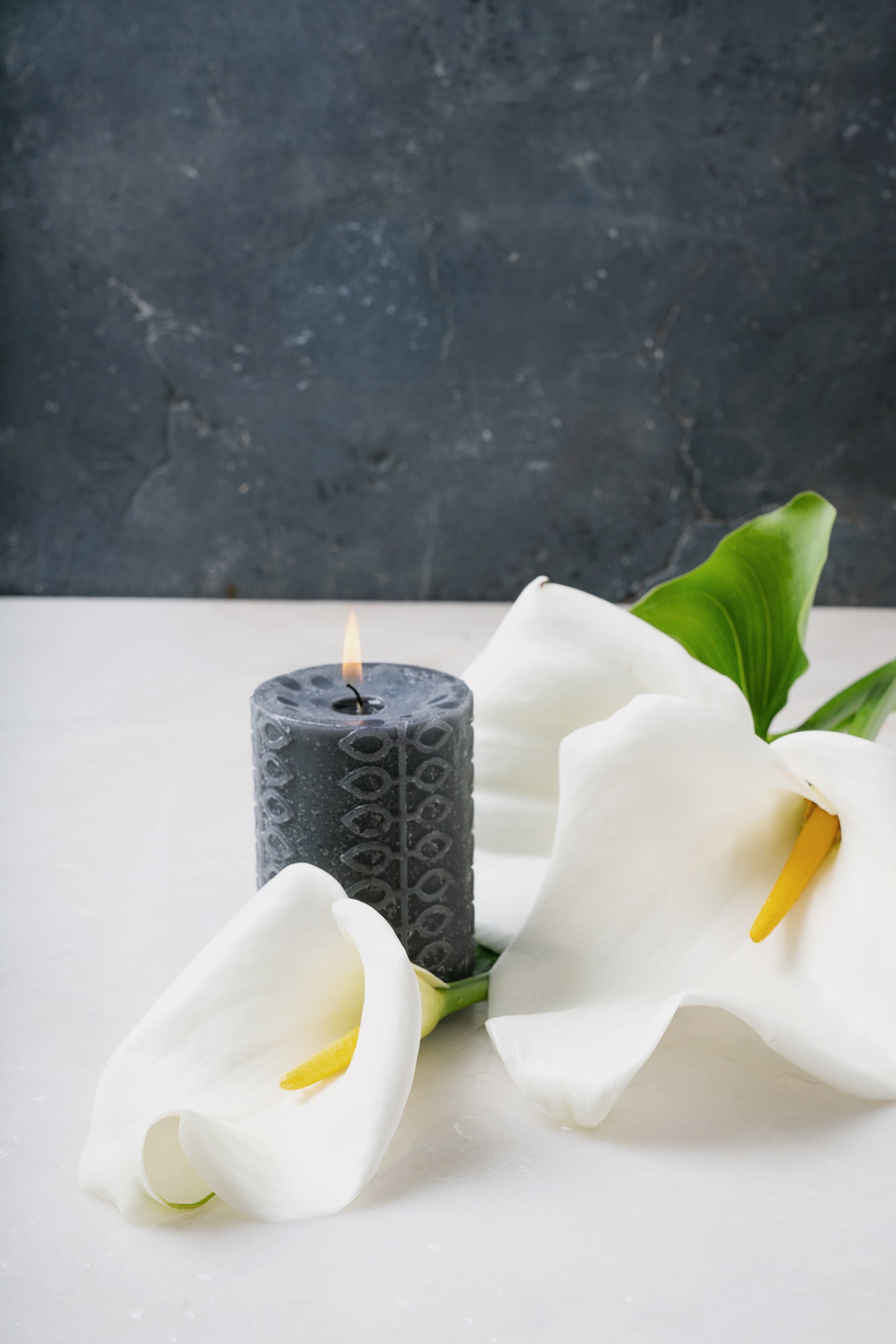 White Calla Lilly flowers with burning black candle